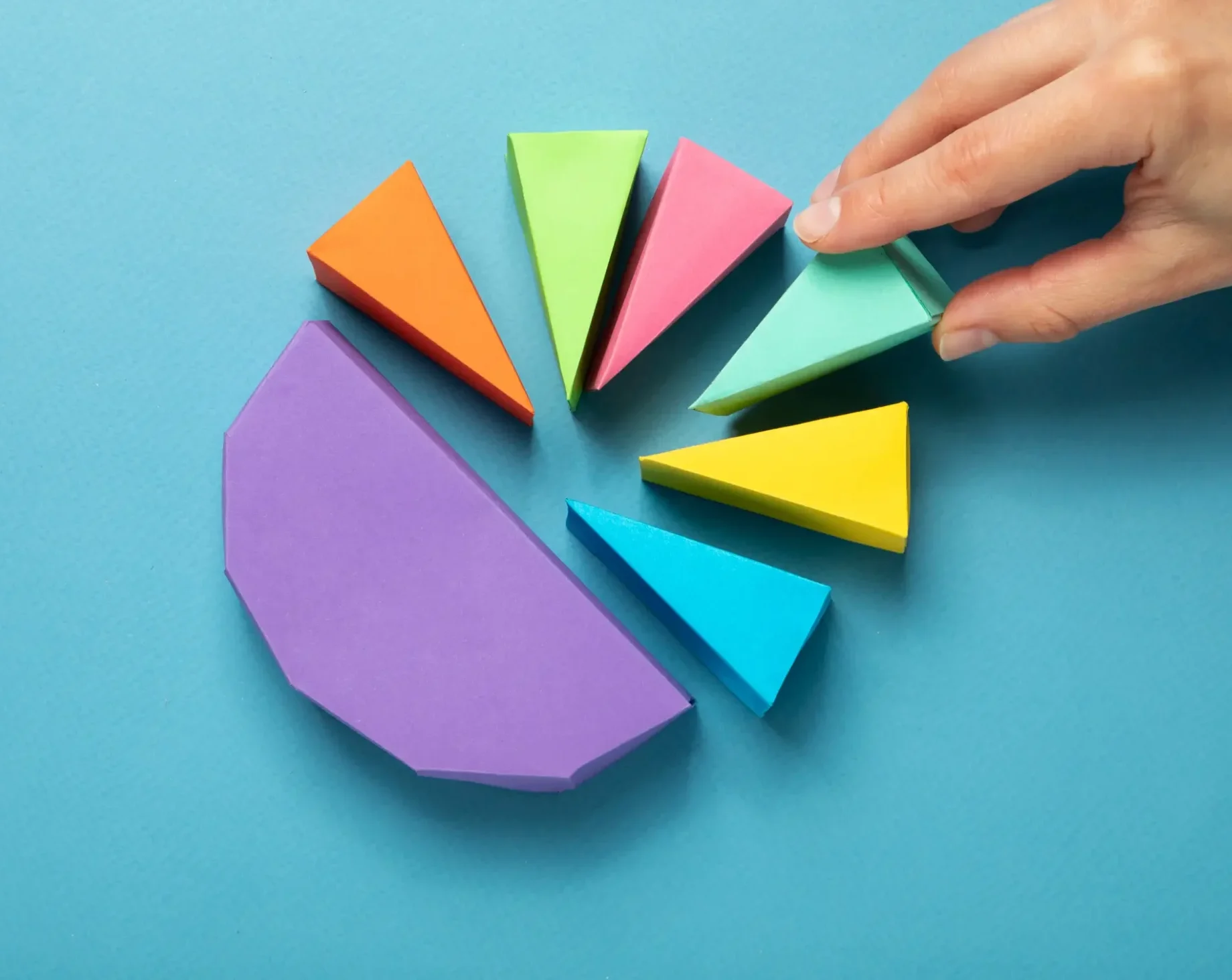 Hand adjusting colourful pie chart segments representing diversified portfolio asset allocation.