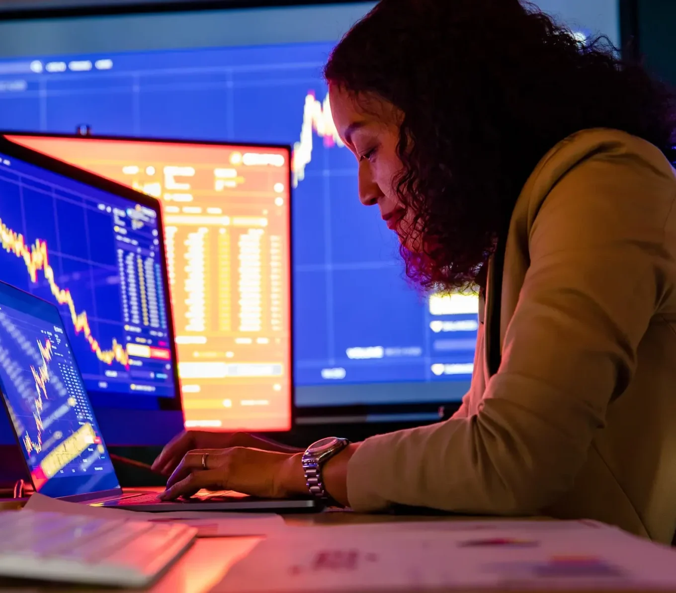Portfolio manager monitoring live market prices on multiple trading screens in dealing room.