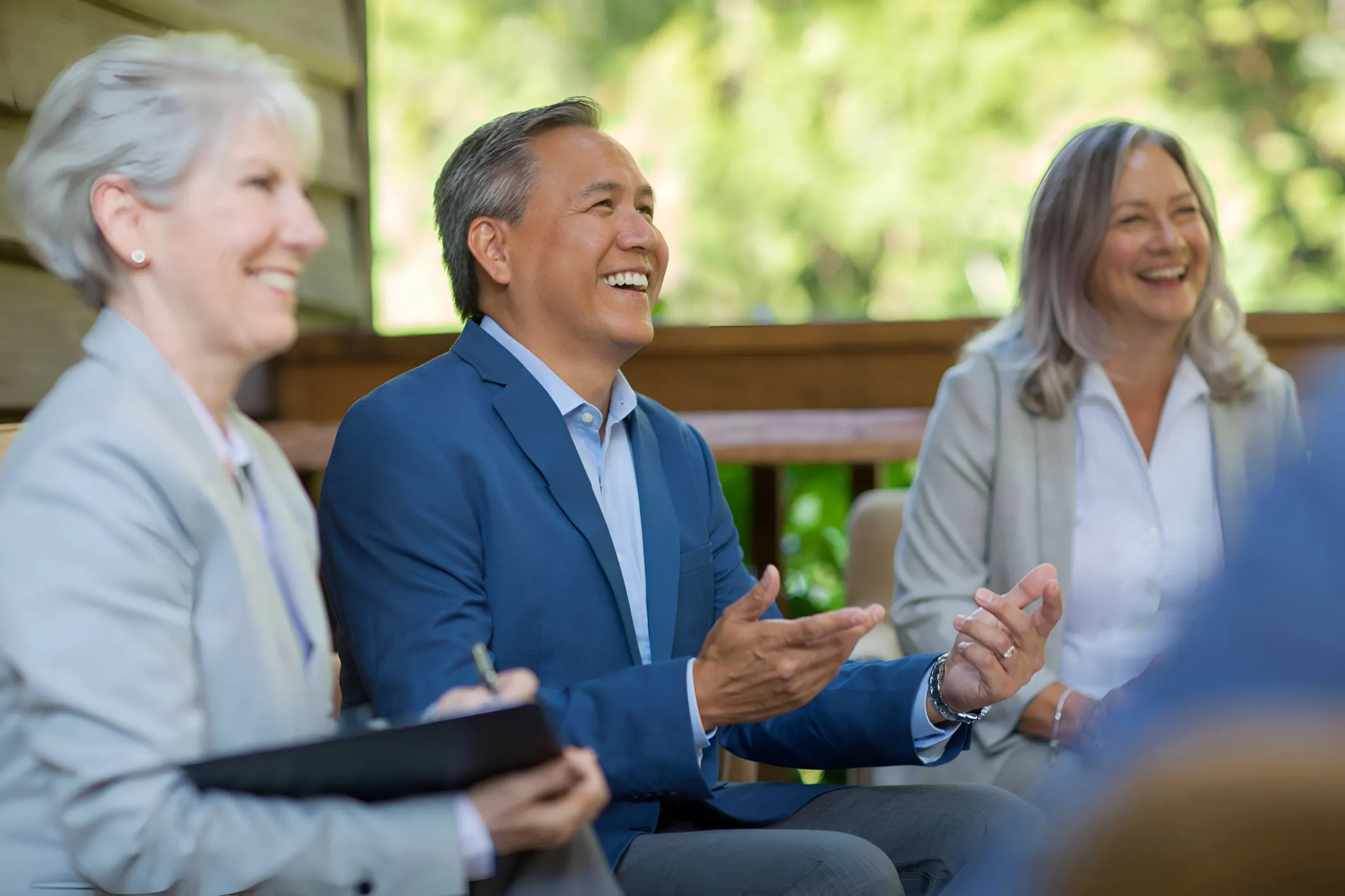 Senior investment leaders sharing ideas and laughing together during informal client relationship meeting.
