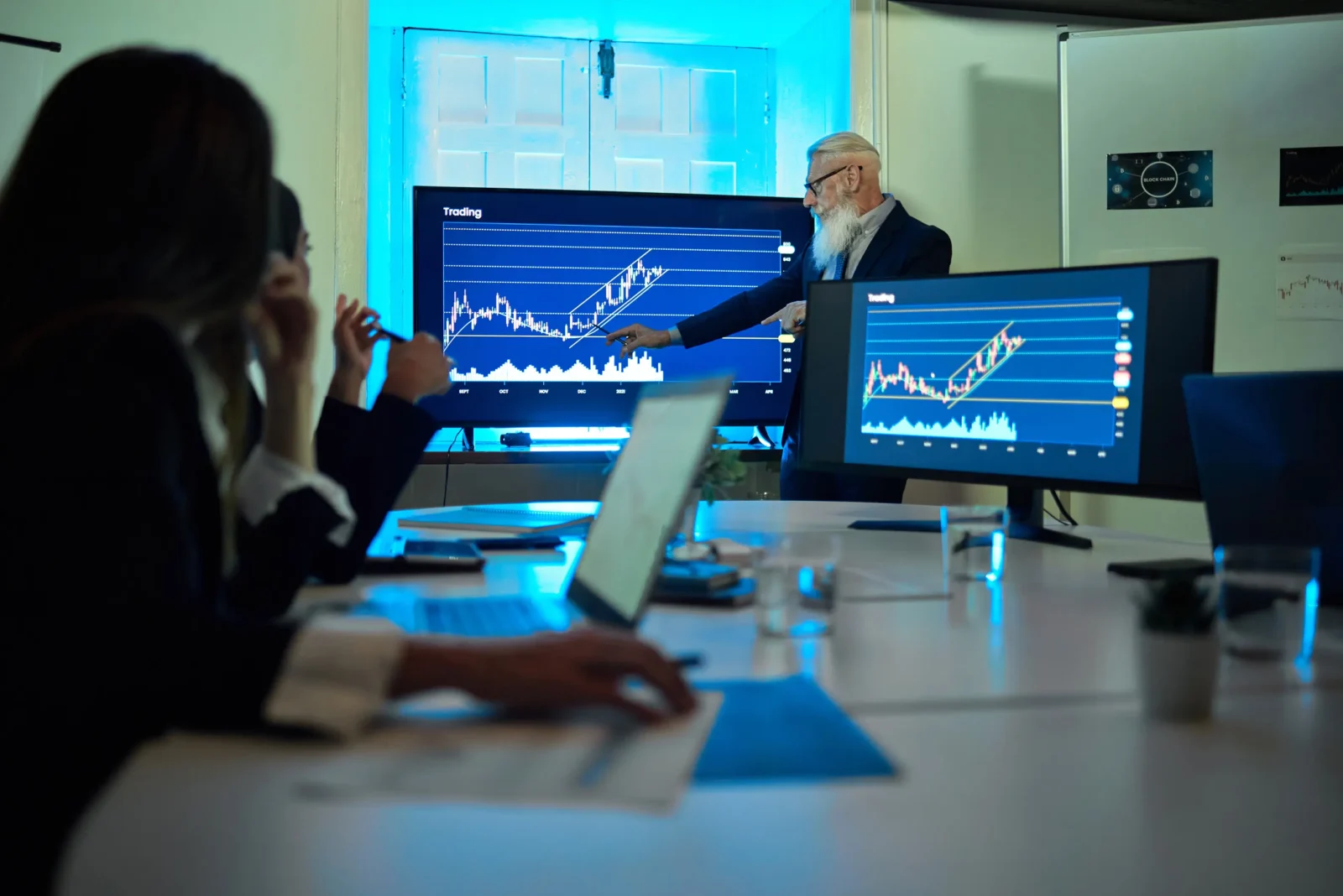 Senior investment strategist presenting rising market trend charts to team in trading strategy meeting.